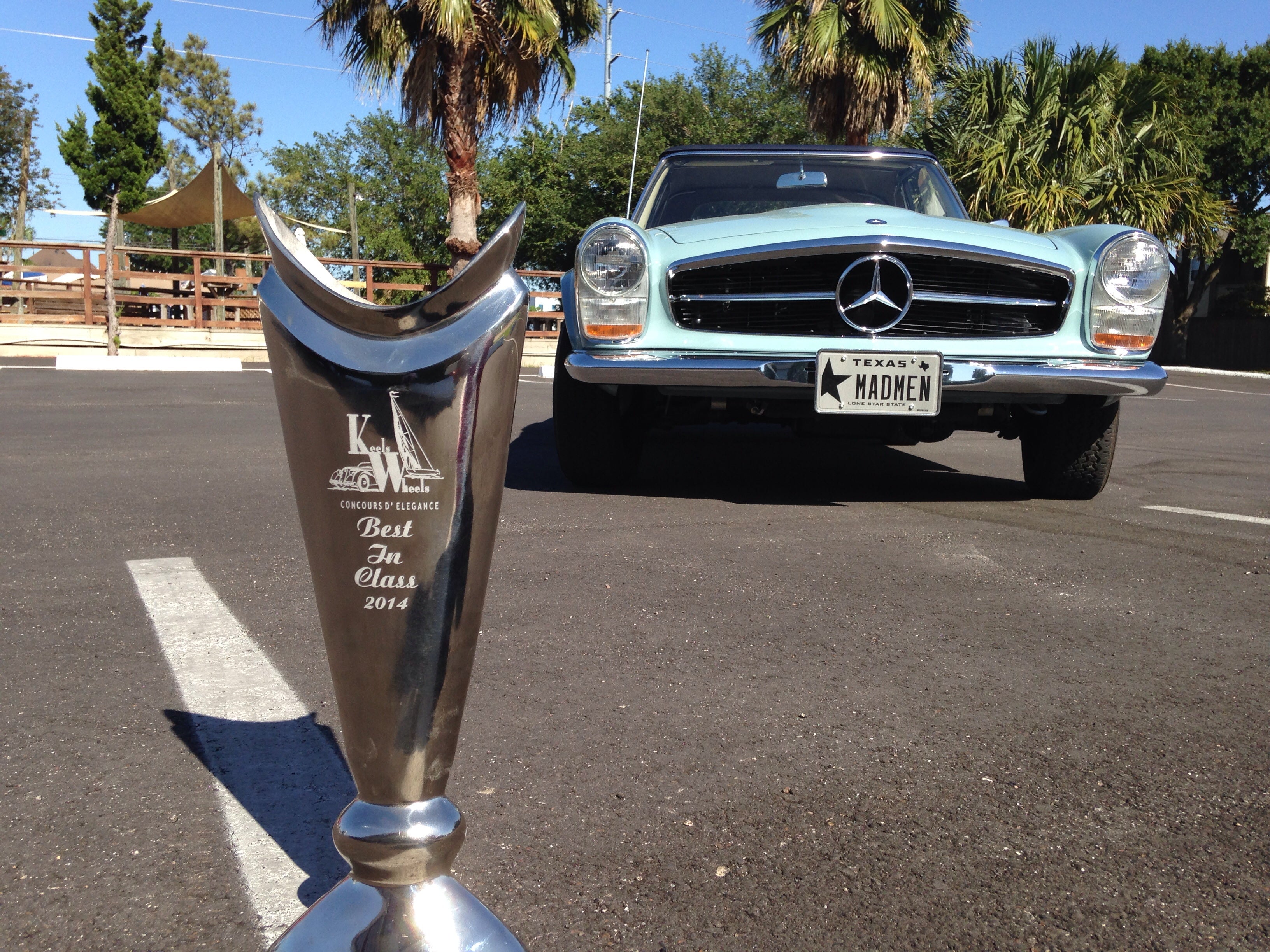 Mercedes-Benz car with a concours D' Elegance "best in class" trophy in the foreground on a parking lot