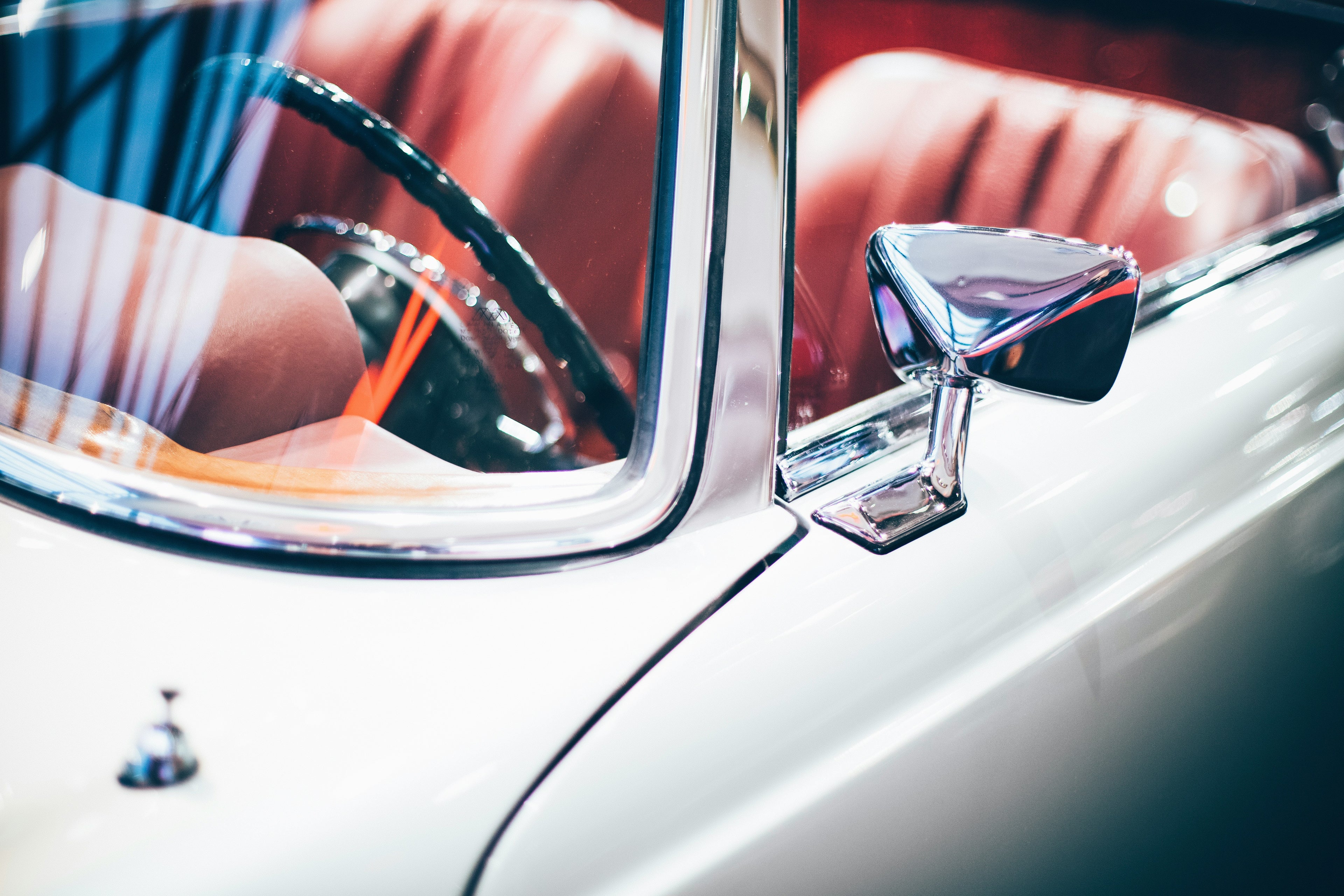 Close-up of a classic car's side mirror with a blurred background